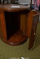 View of the drum table with door open, showing interior storage space and wood paneling.
