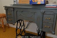Front view showing the painted cabinet and treadle iron base with brass knobs on drawers.