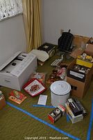 Photo of multiple kitchen items arranged on carpet showing boxes, enamel pot, and other items.