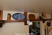 Wide view of shelf showing ceramic steins, blue turkey platter, amber rectangular platter, and small ceramic items.