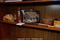 Shelf with multiple pottery pieces including vase, bottle, large pot with patterns, and wooden boxes and carved items.