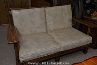 Front angle view of a wooden frame loveseat with beige cushions on seat and backrest, showing armrests and wood grain.