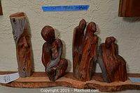 Overview of four carved wooden sculptures by Sophie Cowman on wooden base, varying humanoid abstract forms.
