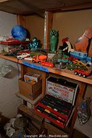 Shelf with assorted vintage toy vehicles and figurines including cars, trucks, tank, and collectible figures.