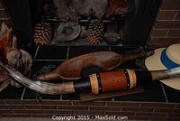 Photo showing wooden cattle yoke, mounted Texas Longhorn horns on wooden plaque, and assorted wood pieces on black tiled hearth.