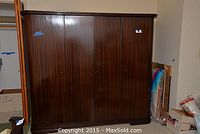 Closed view of large dark wood wardrobe with four doors and polished finish.