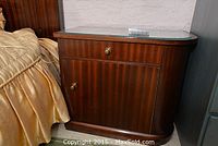 Nightstand showing front with drawer and cabinet door, dark wood, glass top.