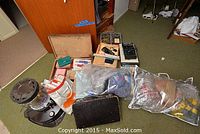 Overview of the lot showing kerosene heater, sewing pattern bags, and miscellaneous boxes and electronics