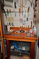 Workbench and surrounding pegboard with tools and items on shelf below work surface
