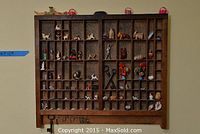 Full view of wooden printers tray filled with various small collectibles including animals, angel, baskets, and shells.