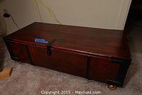 Front exterior view showing red-stained finish, black metal hardware and brass caster wheels