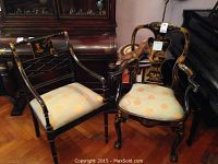 Two black lacquered chinoiserie armchairs with floral and landscape motifs, one with ball and claw feet and fiddle back, the other with straight turned legs and diamond-shapped splats.