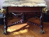 Front view showing marble top, carved apron, twisted rope legs, and brass lion head accents