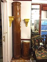 Four cylindrical wooden cabinet sections stacked vertically, medium brown polished wood, brass knobs visible on doors, freestanding floor unit.