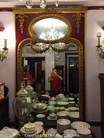 Full view of red painted wooden mirror with gilt frame, oval top section and rectangular bottom section