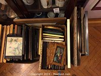 Collection of assorted framed art pieces in box