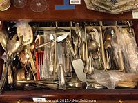 Full drawer view with mixed flatware trays and loose serving pieces