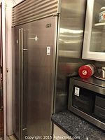 Full view of stainless steel Sub-Zero refrigerator installed next to countertop microwave