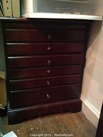 Front view of closed dark wood cabinet showing six drawers with drop ring pulls