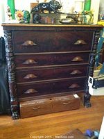 Full front view showing four drawers, carved columns, and items on glass top