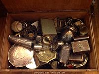 Top view of open plywood chest filled with assorted metalware and boxes