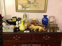 Full overview of assorted vases, figurines, shot glasses and boxes on dresser