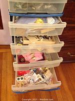 Five-tier plastic drawer organizer filled with mixed jewelry items