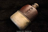 Angled side view illustrating the thick leather wrap around the glass flask with visible wear and metal components.