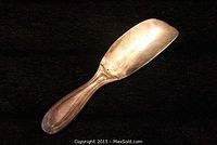 Side view of the sterling silver shoehorn showing its weighted handle and blade with some surface dings.