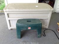 Full view of beige Suncast deck box with green plastic yard stool placed in front, showing overall size and condition.