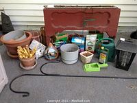 Wide view of the lot showing large wood planter stand, mixed ceramic and plastic pots, watering cans, bug zapper light, and plant fertilizers.