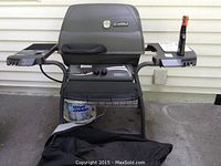 Full view of Kenmore propane grill with side burner, propane tank underneath, and grill cover on the ground in front
