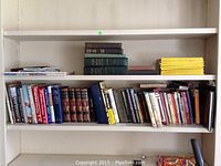 Shelf with multiple vintage and classic hardcover and paperback books of various titles and sizes, including The History Of Butler County volumes, Huckleberry Finn, People From Dickens, and The Art of Treasure Island.