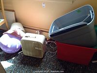 Fan, plastic bins, purple exercise ball, rag rug rolled, and part of chair visible