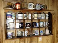 Three wooden curio shelves filled with souvenir mugs and decorative cups. Shelves have spindled dividers and scalloped edges.