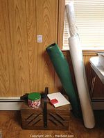 Wooden sewing box with fabric rolls beside it, green tin of buttons on top
