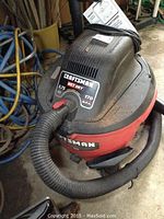 Front view of Craftsman shop vac displaying brand, power specifications, and hose attachment.