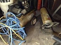 Craftsman air compressor paint sprayer with attached hoses and portable kerosene heater beside it on floor