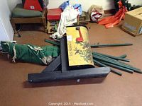 Side angle showing large yellow mailbox mounted on black wooden post base, green metal poles and green hammock fabric tightly rolled with rope.