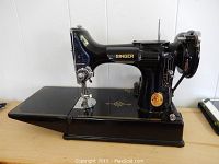 Side view of Singer Featherweight sewing machine on wooden surface showing overall condition and gold decals
