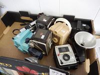 Overview of multiple vintage cameras in a box, showing different styles and colors