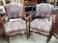 Front view of two cherry wood armchairs with Aztec tribal pattern fabric upholstery showing turned legs and minor wear.