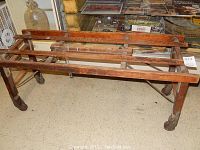 Angled view of antique wooden drying rack showing four caster wheels and overall construction.