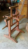 Frontal angle of the wooden yarn winder showing the crank handle, crossbars, and base.