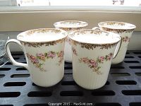 Four Royal Albert chocolate mugs arranged closely, showing floral rosebud designs and gold decoration near rims.