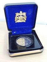 Black presentation box open showing the 1968 Canadian dollar coin in clear protective casing on blue velvet interior.