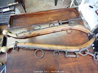 Full view of two wooden horse and buggy brackets with metal rings, laid side by side on wooden surface.