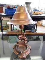 Full view of the 1940s copper cowboy bronco lamp showing lamp shade and base on glass table.