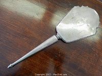 Full view of the sterling silver hand mirror showing the handle and back design on a wooden surface.