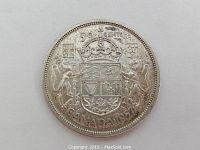 Obverse side of 1957 Canadian 50 cent coin clearly showing value and coat of arms details.